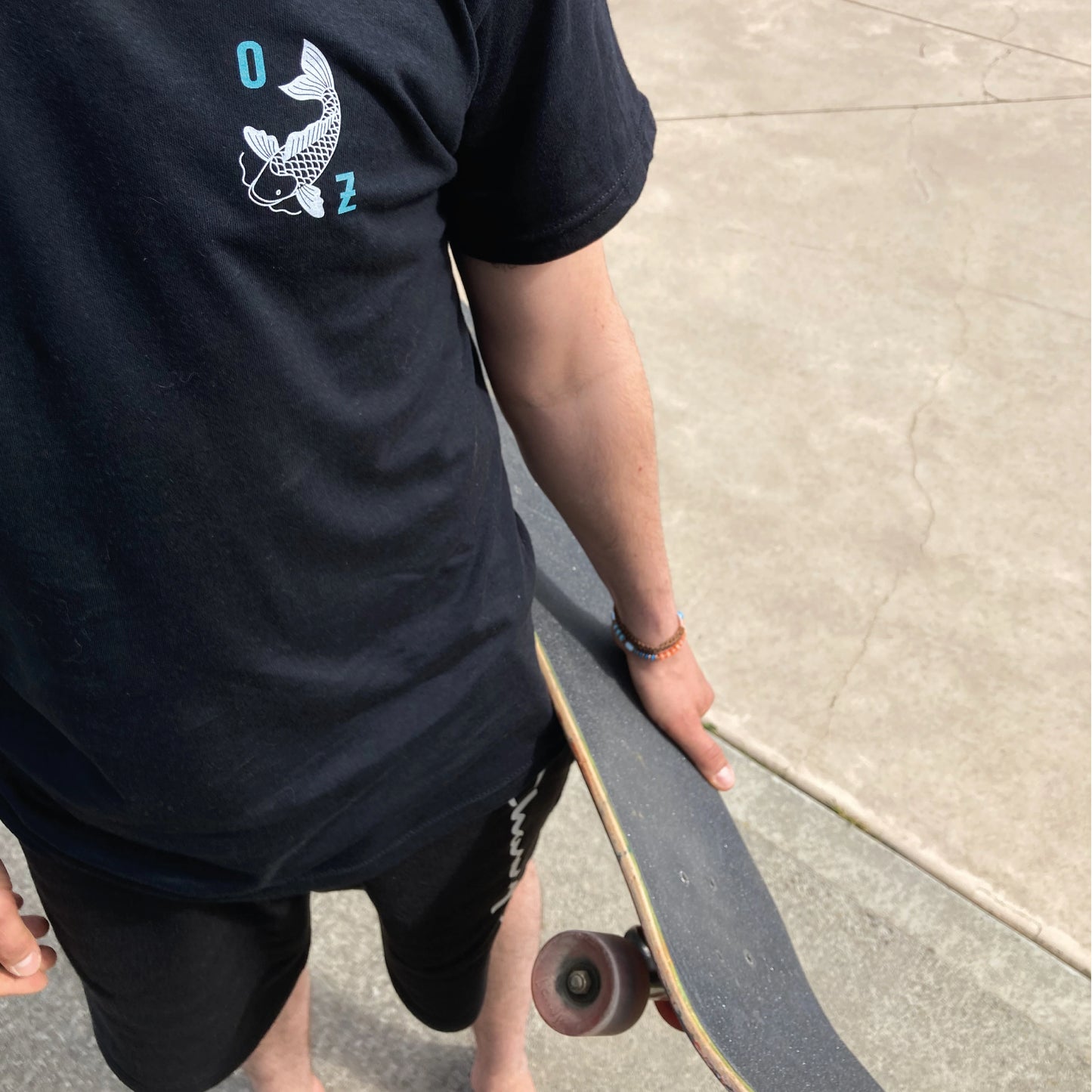 Photographie en plongée d'un homme portant son skateboard à la main.
