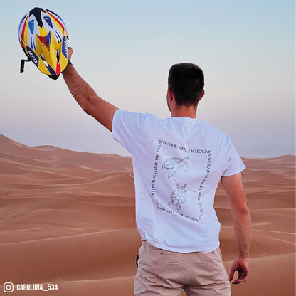 Photographie d'un homme dans le desert portant un tshirt graphic blanc avec des tortues imprimées en vert dans le dos