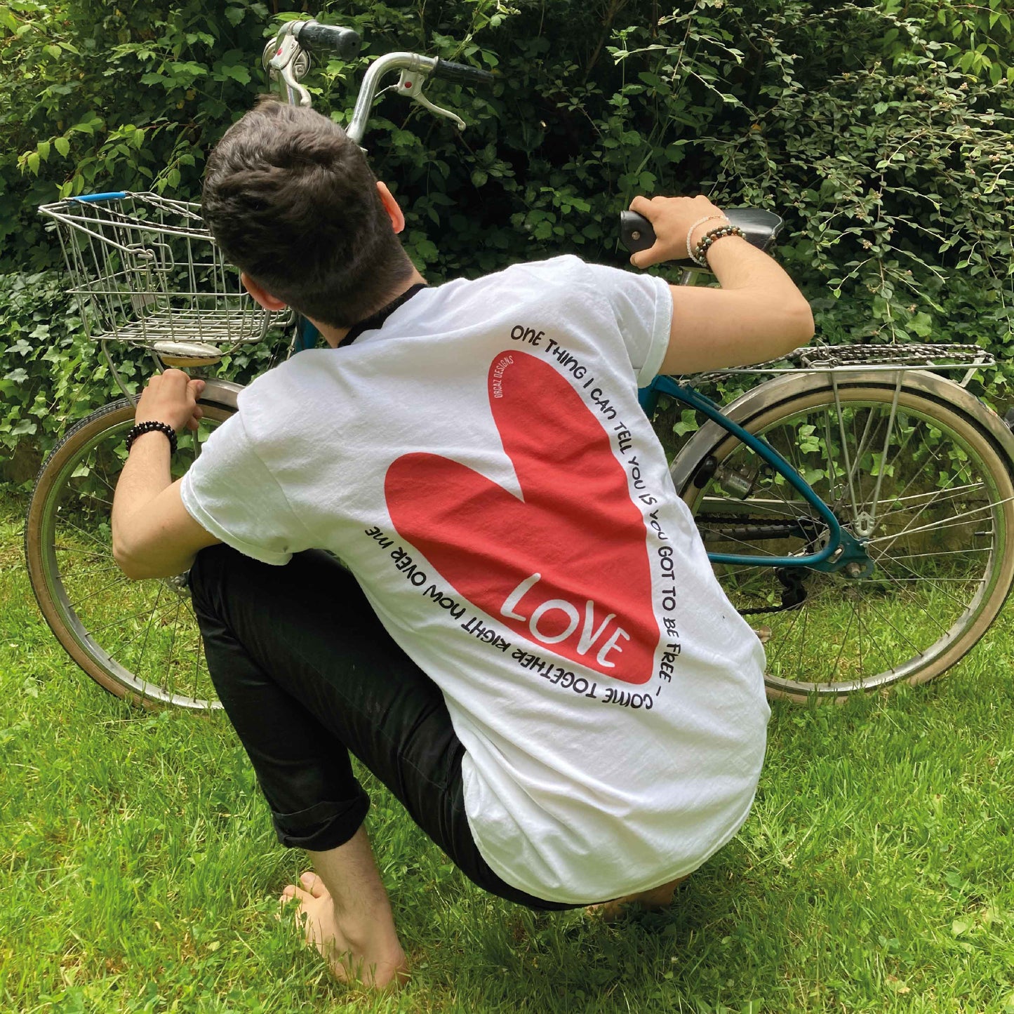 Photographie d'un tshirt blanc porté par un jeune homme avec un grand coeur rouge imprimé dans le dos avec des paroles de chanson des beatles