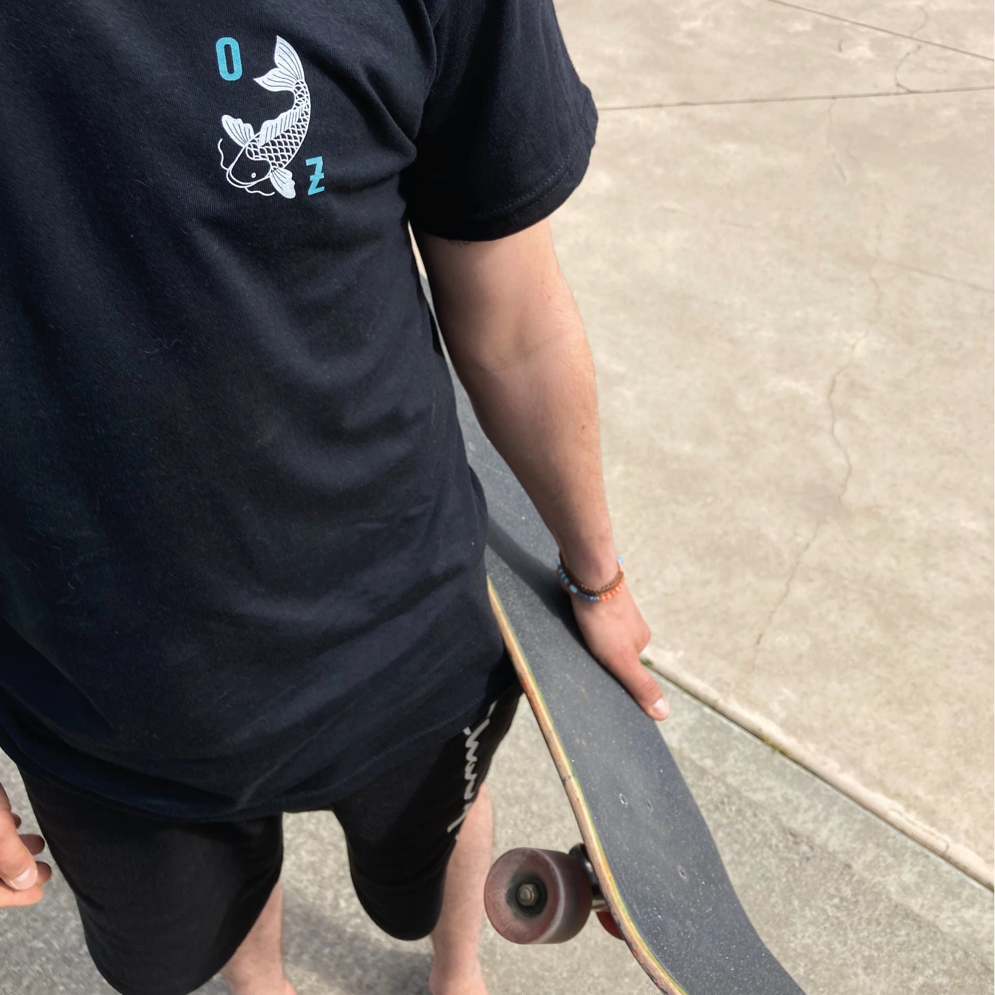 Photographie en plongée d'un homme portant son skateboard à la main.